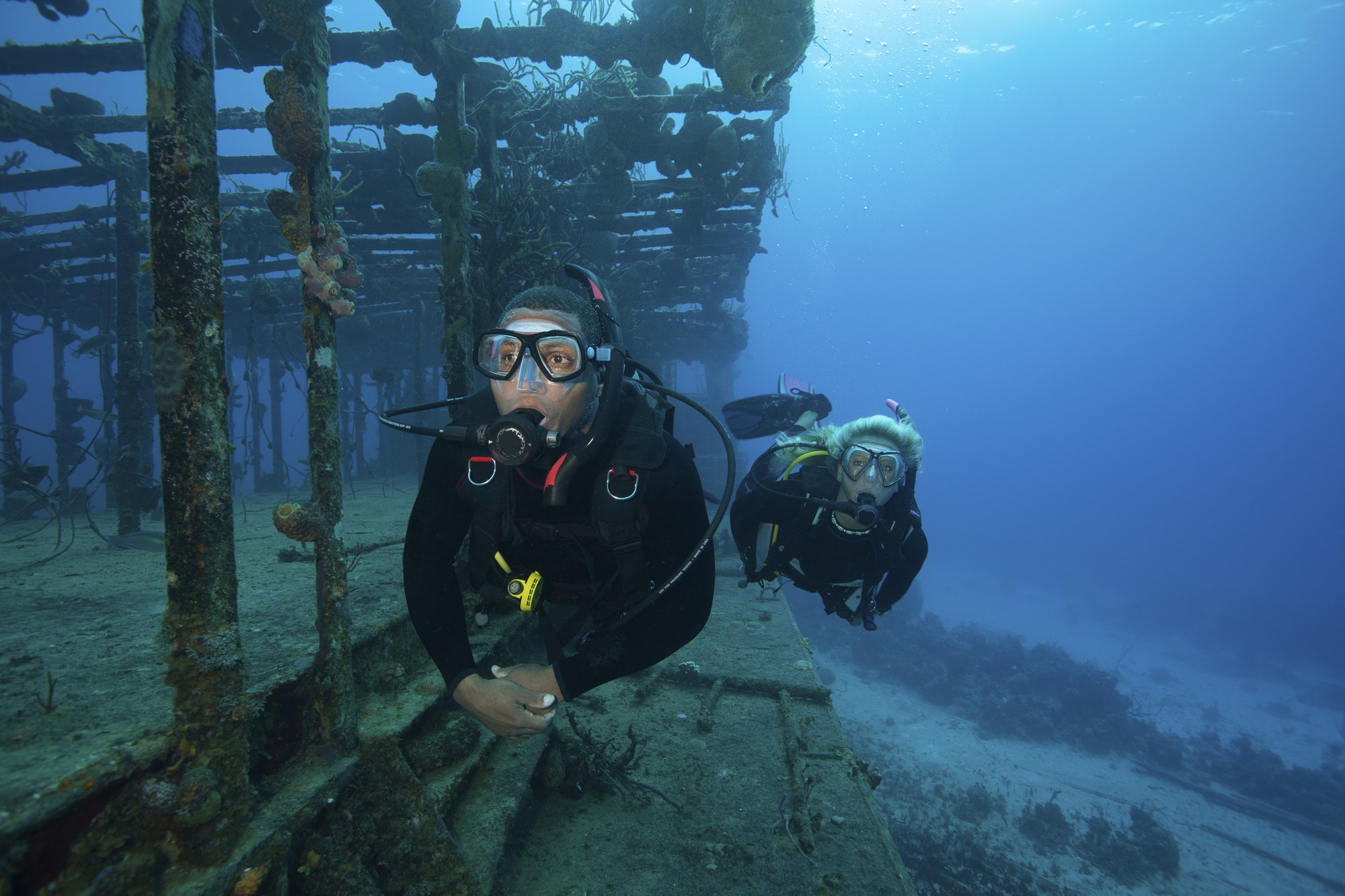 two-divers-swimming-along-the-remaining-structure-of-a-shipwreck-.jpg
