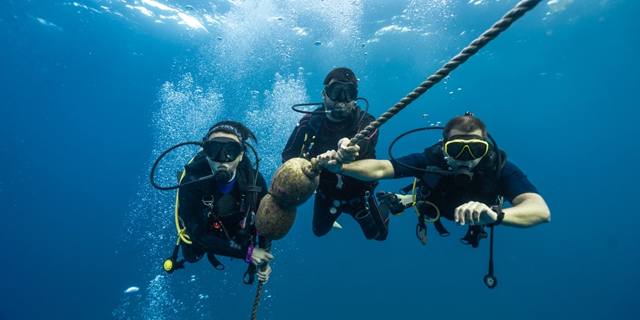 Three,Professional,Diver,Checking,His,Dive,Computer,To,As
